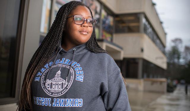 A student poses for a photo while wearing a sweatshirt that says “Westfield State Criminal Justice.”