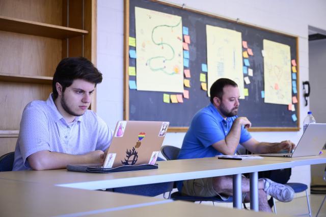 西方大众写作计划 two 学生 with laptops focused on projects