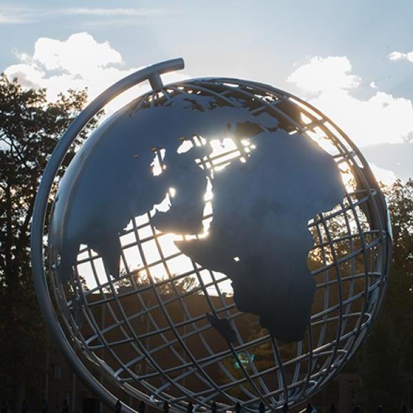 Sunlight shines through the globe sculpture on the campus green