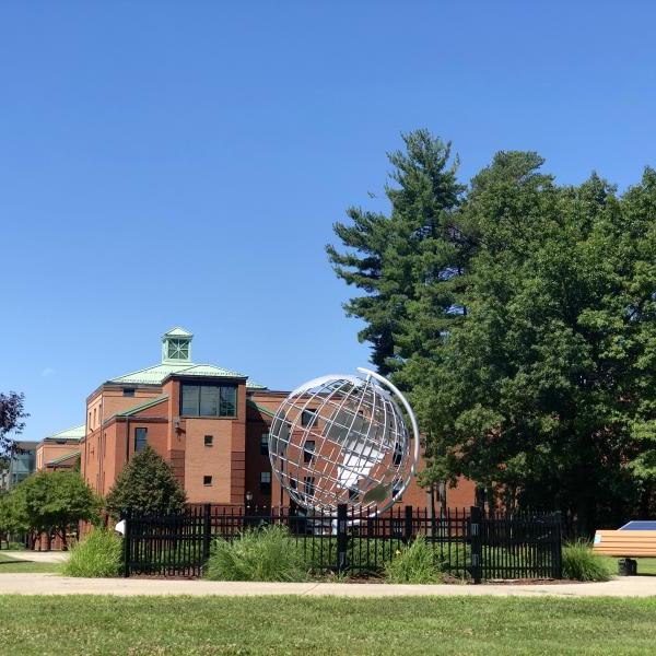 image of the globe on the campus green with Courtney Hall in the background