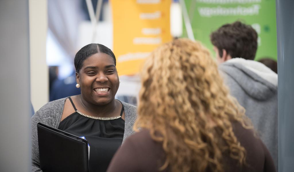 Smiling female talks with a prospective employer at the Career Fair