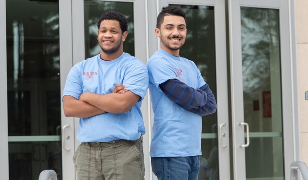 两个学生在帕伦佐前面，背对背地穿着华盛顿州立大学的蓝色衬衫，双臂交叉.